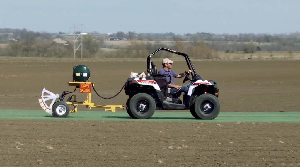 An ATV rolls out sod netting across a freshly prepared field.